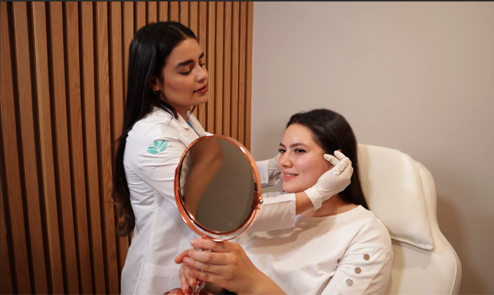 Dermatóloga de María Linda mostrando a una paciente su diagnóstico con un espejo
